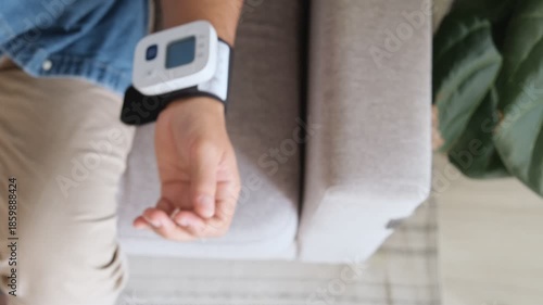 Senior man at home using a digital tonometer to check his blood pressure and pulse