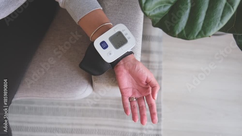 Woman monitoring blood pressure and pulse at home with a medical device