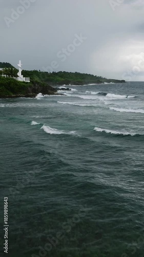 Dark ocean water with waves rolling toward tropical hillside coastline. Siargao, Philippines.