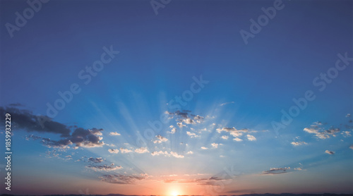 Radiant sunrise breaking over a dark horizon with golden rays streaming through scattered clouds into a vast blue sky, symbolizing hope, new beginnings, and uplifting morning energy


