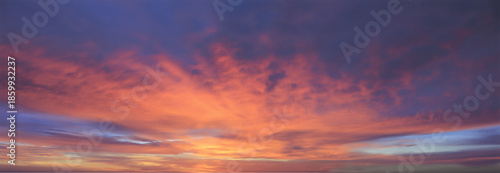 Fiery panoramic sunset sky bursting with intense orange, red, and purple streaks radiating from the glowing horizon, painting the clouds with dramatic, powerful, yet calming energy

