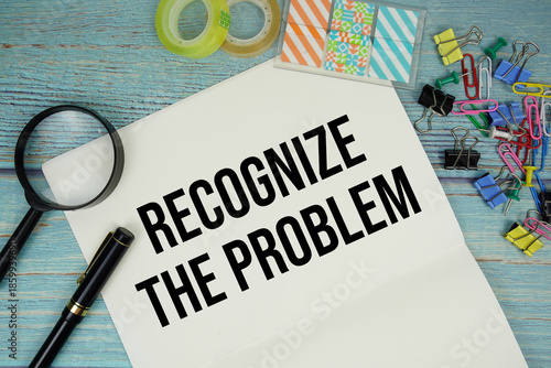Fotografia Recognize The Problem text on a paper surrounded by office supplies and magnifyi