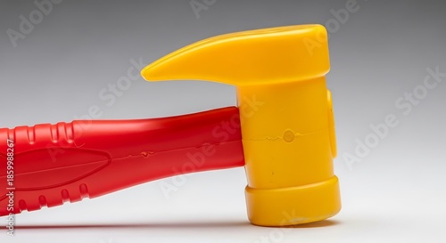 Vivid red and yellow plastic toy hammer contrasting against soft backdrop