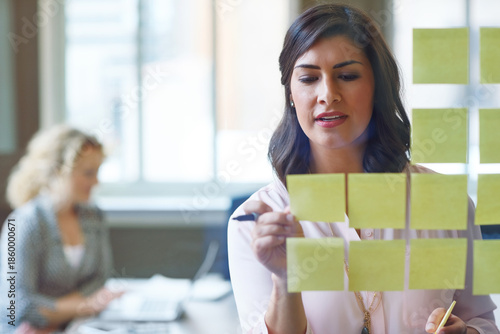 Woman, sticky note and glass wall in office for vision, business development and campaign planning. Creative team, brainstorming or moodboard in meeting for workflow, project management or set goals