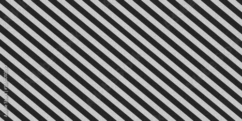 Diagonal black and white striped pattern background with grainy noise texture. Seamless repeat slanting lines backdrop for modern graphic design