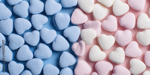 Overhead view of numerous pastel blue pink and white fluffy heart marshmallows split equally across the frame