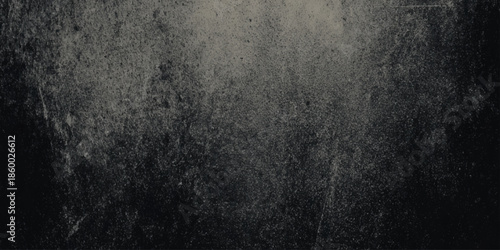 A dimly lit grainy and textured dark gray surface with subtle variations in shading and tone