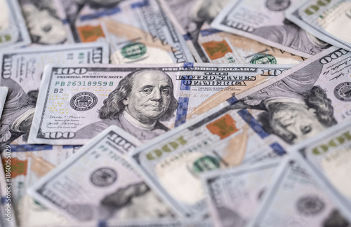 Money background with dollar bills. Texture of US dollars. 100 USD banknotes in focus. American hundred-dollars notes spread on a table. Pattern of US dollars for finance concept. Dollars currency. © Volodymyr