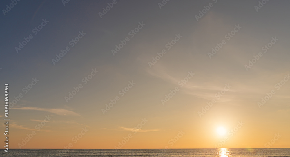 Fototapeta premium Sunset sky clouds over sea water background in evening with orange, blue sun light, Horizon sea ocean sunrise sky landscape nature backgrounds and gold sun down in golden hour summer season, Dusk sky