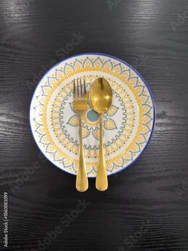 A beautifully decorated rice plate, along with a spoon.