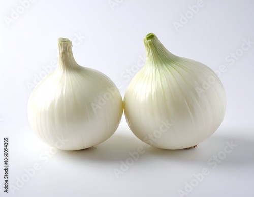 Two fresh, white onions with green stalks on a plain, light background
