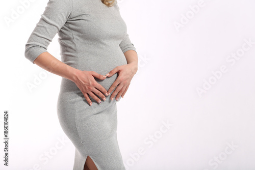 Pregnant woman wearing a light dress on a white background, expressing purity, motherhood, calm ожидание, and gentle feminine beauty