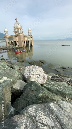 Vertical view of the iconic Palu Floating Mosque ruins in Central Sulawesi, partially submerged after the 2018 earthquake and tsunami. A symbol of resilience and natural disaster impact.
