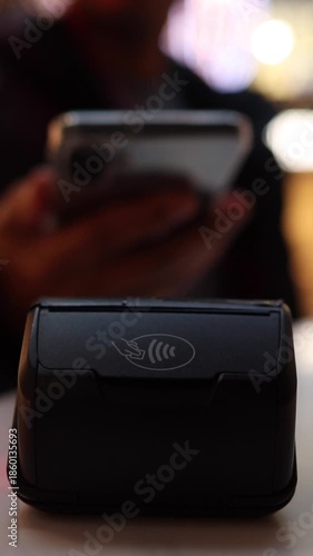 Hand of a shopper using a smartphone to make a contactless payment
