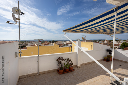 Rooftop terrace with striped awning and panoramic sea view over rooftops