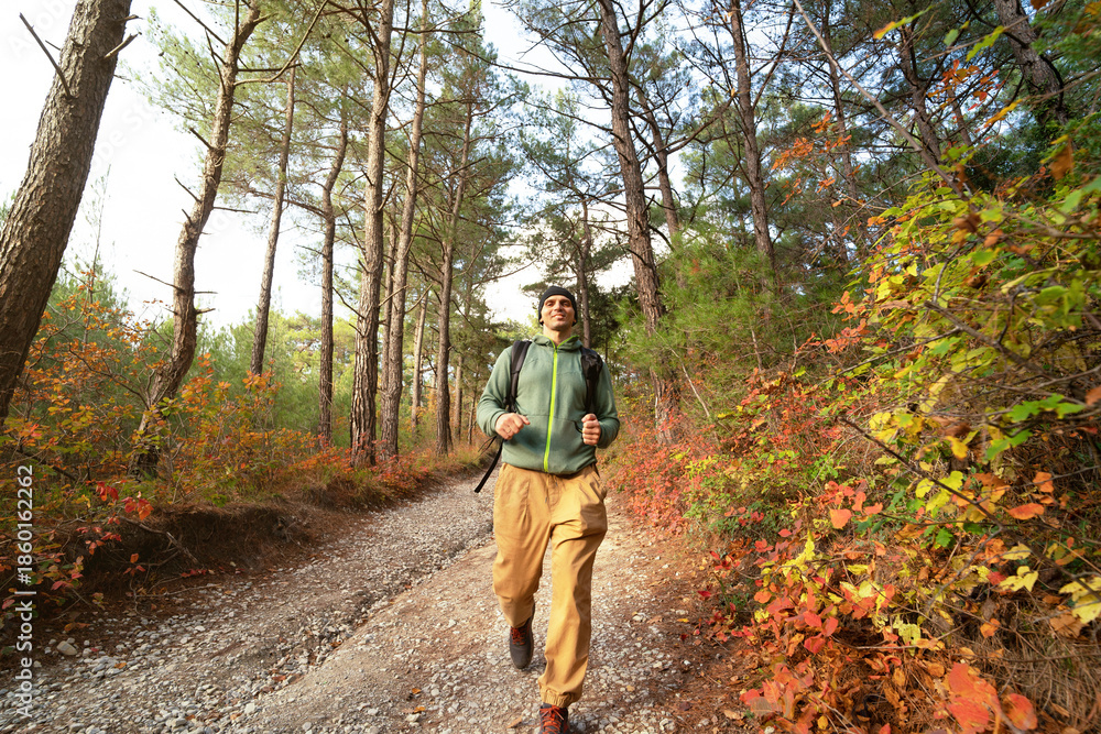 Naklejka premium Happy runner on the forest path in autumn