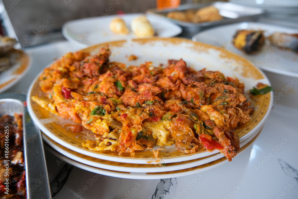 Fototapeta premium Telur Dadar (Indonesian omelette) served on a ceramic plate. The omelette is thick, crispy, heavily textured with green onions and red chilies, reflecting a common staple in Southeast Asian cuisine