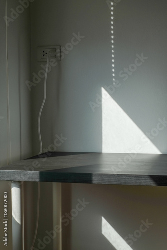 Empty white cement wall room and black table with shadow from window.