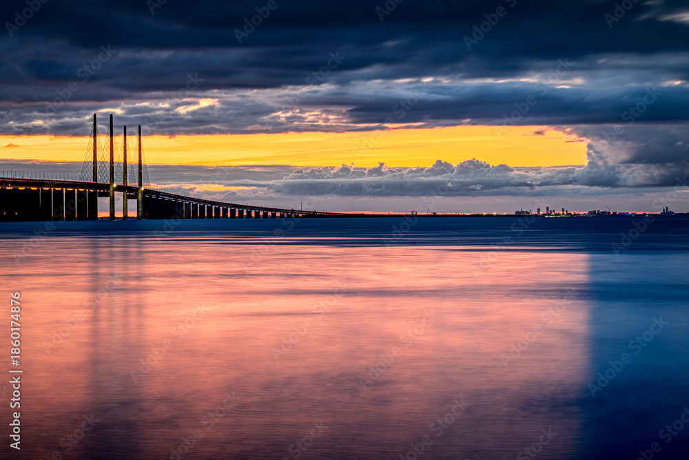 Fototapeta premium Øresund Bridge during amazing sunset, view of Copenhagen city from Malmo, Sweden. Building structures connecting two points.
