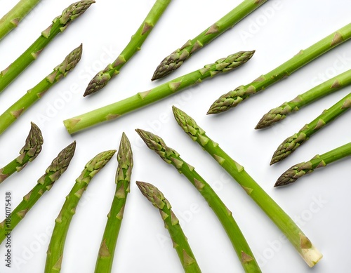 Close-up of fresh, green asparagus spears scattered on a white surface