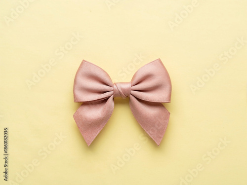 Soft pink fabric bow isolated on yellow background with minimal flat lay composition gift decoration and feminine design