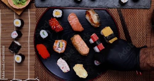 High-quality close-up of fresh assortment sushi rolls served on a dark plate, featuring vibrant colors, fresh fish, laid on slate board bamboo mat chopsticks