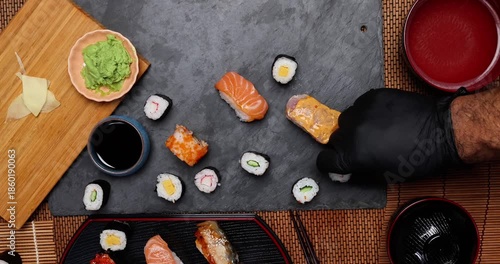 High-quality close-up of fresh assortment sushi rolls served on a dark plate, featuring vibrant colors, fresh fish, laid on slate board bamboo mat chopsticks