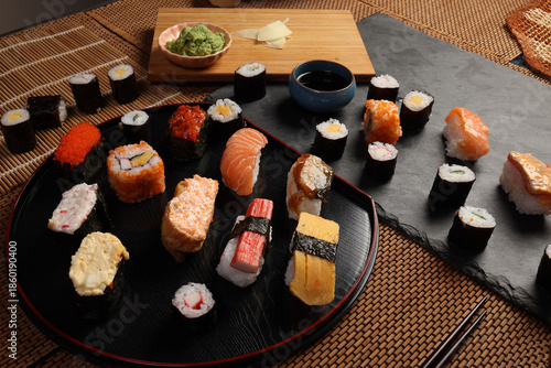 High-quality close-up of fresh assortment sushi rolls served on a dark plate, featuring vibrant colors, fresh fish, laid on slate board bamboo mat chopsticks