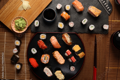 High-quality close-up of fresh assortment sushi rolls served on a dark plate, featuring vibrant colors, fresh fish, laid on slate board bamboo mat chopsticks