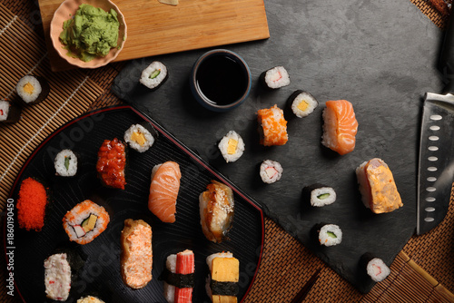 High-quality close-up of fresh assortment sushi rolls served on a dark plate, featuring vibrant colors, fresh fish, laid on slate board bamboo mat chopsticks