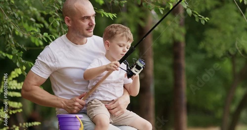 Loving father shouts with delight at small movement of rod. Dad helps preschooler blond son pull fishing rod with care and joy. Man whispers words of support