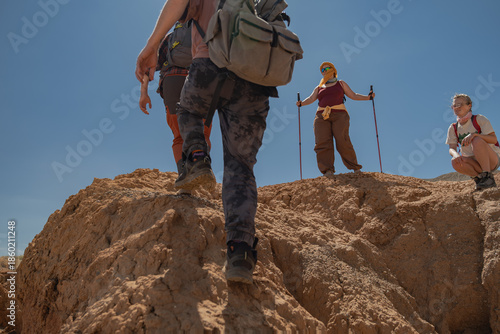 Obraz na plátne A group of tourists with backpacks and trekking poles ascends a mountain slope in the Mongolian desert