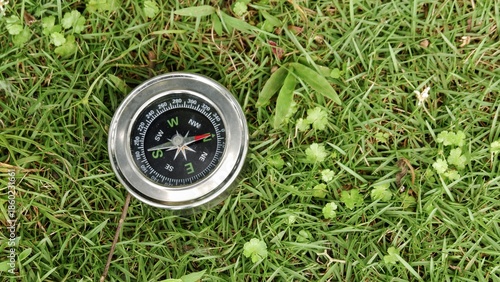 Obraz na płótnie Silver magnetic compass lying on a vibrant green lawn