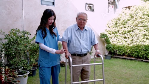 Helping an older man walk in a garden on a sunny day with a caregiver