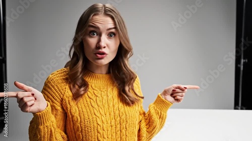 Expressive young woman in a yellow sweater points in different directions with uncertainty