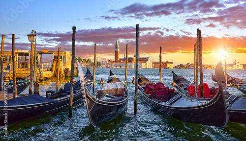 Venice, Italy. View at San Giorgio Maggiore from the Marco Square with Venetian gondolas moored by pear floating on water of Grand Canal. Scenic sunset in venice city..