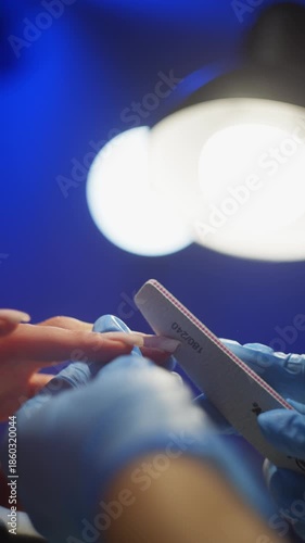 In the rays of light from the lamp, the manicurist creates the perfect nail shape for the client. High quality 4k footage