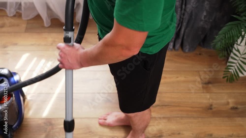 Home cleaning, man vacuuming the floor in the living room. High quality 4k footage