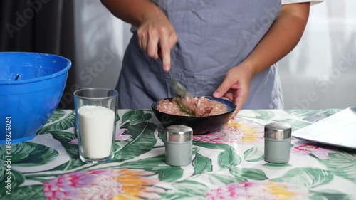 A woman in an apron is mixing minced meat with a spoon. High quality 4k footage