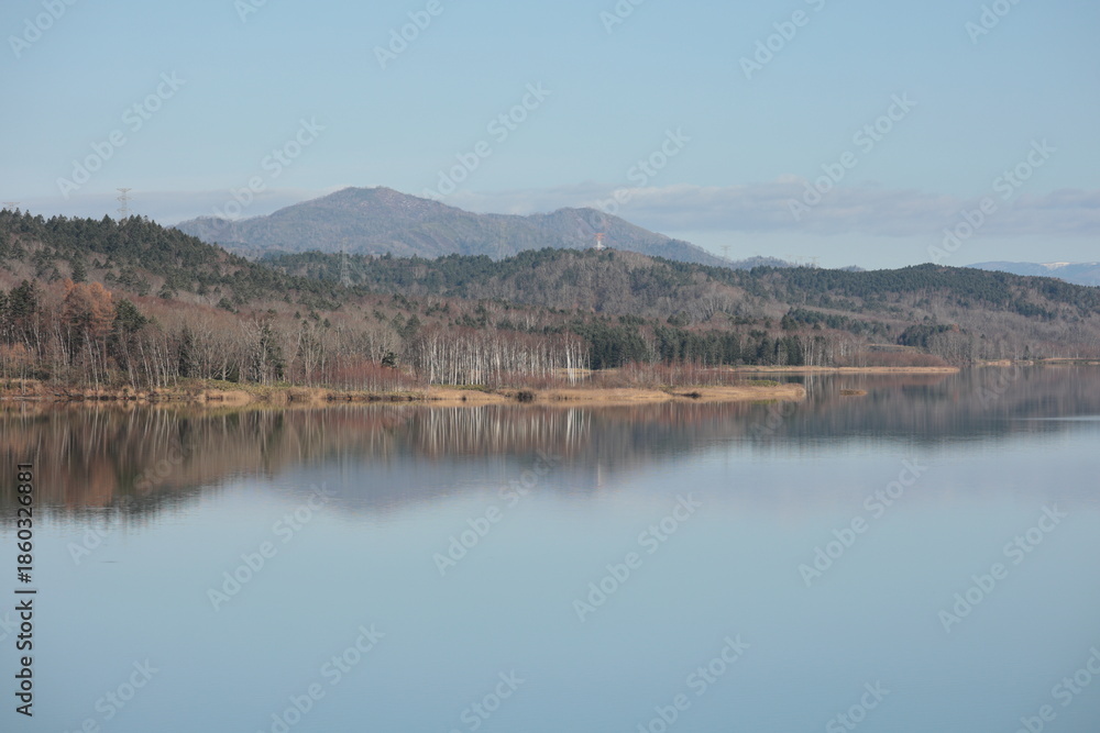 Fototapeta premium 落葉した木々や山々が湖面に映り込む、穏やかな朝のダム湖