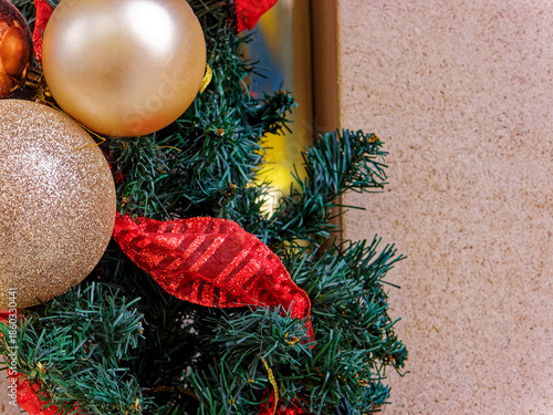Golden Christmas ornaments and red ribbons on a green garland with a neutral stone background for text.