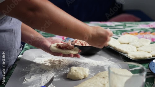 A woman uses a spoon to spread the meat filling onto the dough and forms a pie. High quality 4k footage