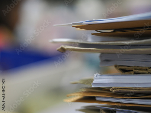 Stack of documents in focus with blurred office background, paperwork concept and shallow depth of field.