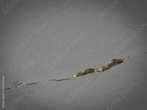 Close-up of cracked concrete wall with peeling red paint, rough texture and urban abstract detail.