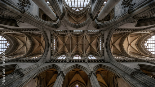 Low angle view of massive Gothic cathedral vaulted ceiling structure | Intricate architectural details of historic European church interior vaults | Symmetrical rib vaulting and flying buttresses