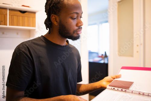 Person with binder and papers at table, home setting