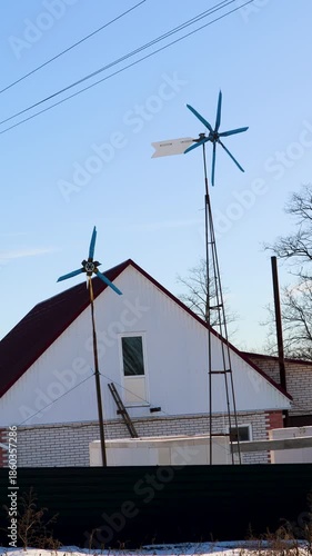 Small homemade wind turbine generating clean, renewable energy in a rural backyard. Alternative power source spinning against a clear blue sky