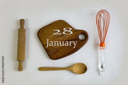 Calendar for January 28: numbers 28, name of the month January in English on a wooden cutting board