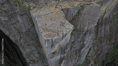 Tourists standing on Pulpit Rock Preikestolen Norway. People gather on the flat rock plateau, taking photos and sightseeing at one of Norway’s most iconic viewpoints.