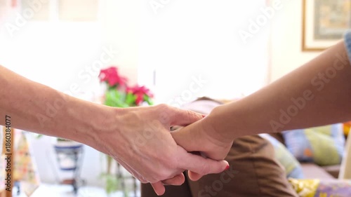 Close up of a senior woman's hand gently holding a younger person's hand. Touching moment representing support, empathy, and comfort